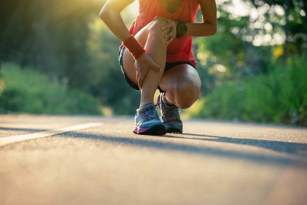 Woman runner stopped on track holding leg