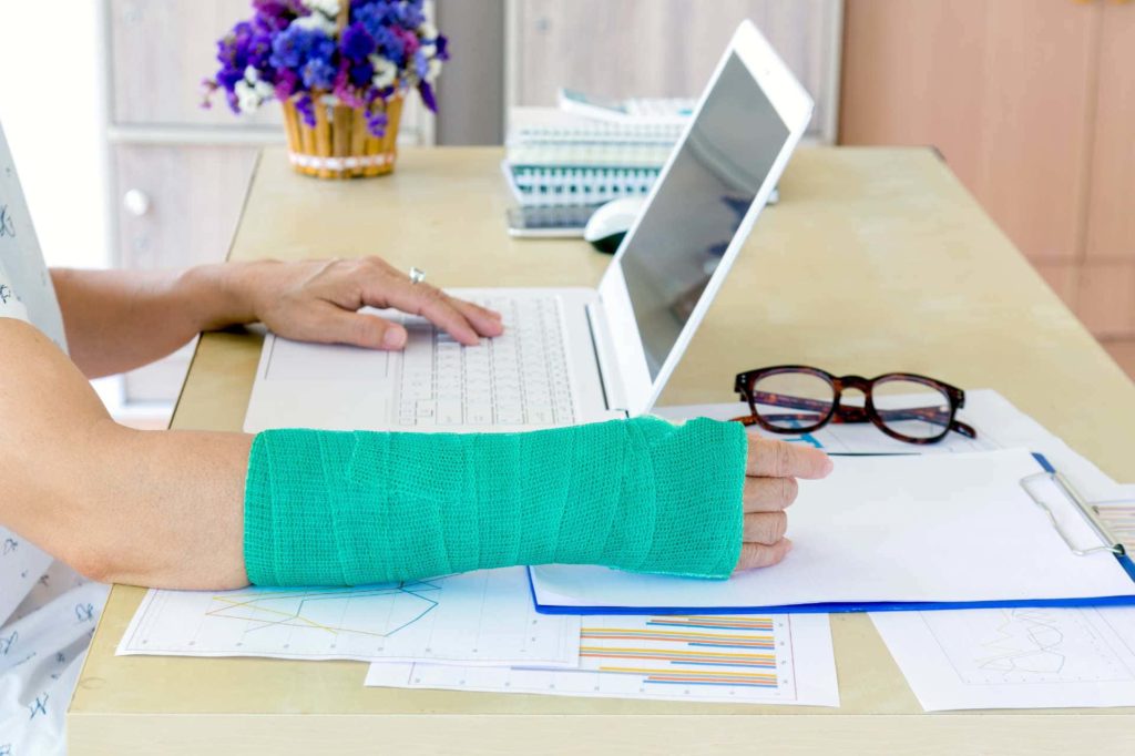 woman in cast working on computer